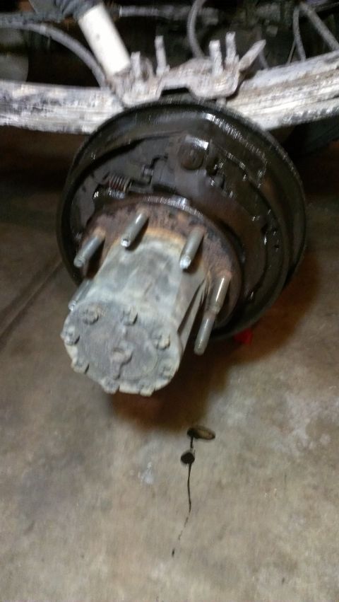 1995 Ford Bronco - The rear axle brake drum assembly is shown, with a fluid drip on the floor.