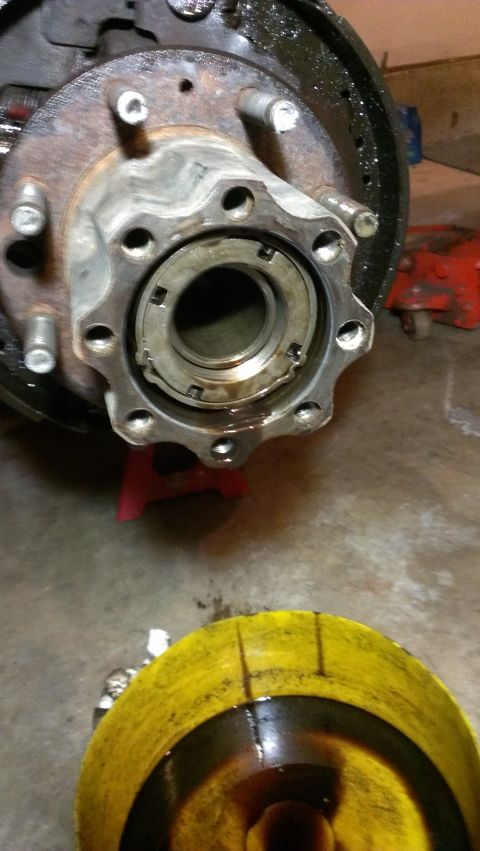 1995 Ford Bronco - Vehicle wheel hub assembly and brake components. A yellow bucket with oil is in the foreground.