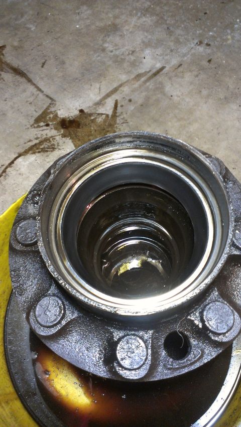 1995 Ford Bronco - A greasy wheel hub assembly is shown, with some fluid stains on the concrete floor in the background.