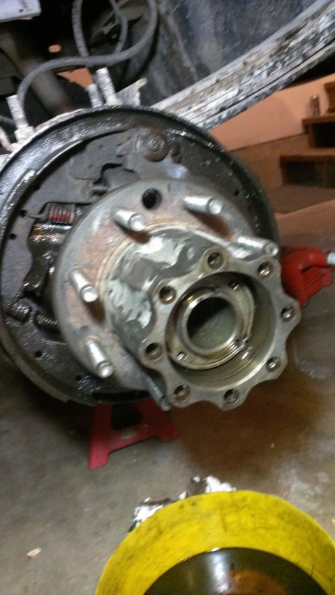 1995 Ford Bronco - Rear axle hub and brake assembly with drum and shoes visible, supported by a red jack stand.