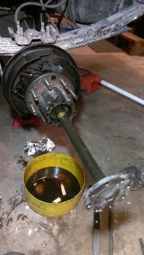 1995 Ford Bronco - The rear axle and brake assembly are shown removed from a vehicle, with a pan of old fluid beneath.