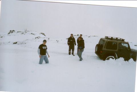 1996 Ford Bronco - A group of people stand around a vehicle that is stuck in deep snow.