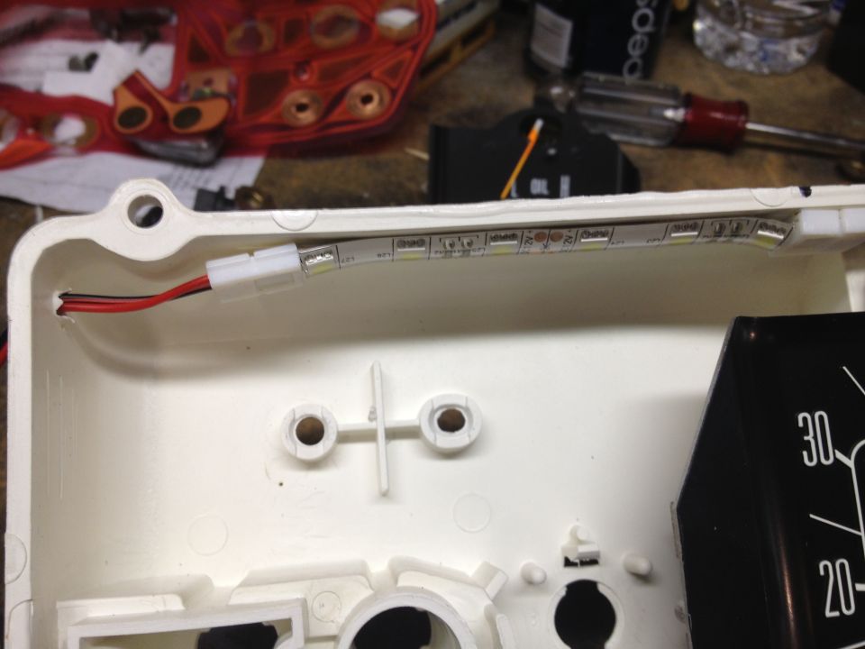 Dashboard interior with a white housing, red wires, and an LED strip. Part of a gauge with markings '20' and '30' is visible