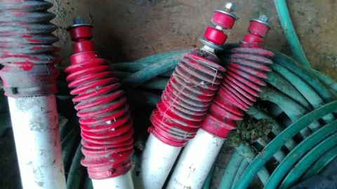 1994 Ford Bronco - Several shock absorbers are shown with a coiled green hose in the background.