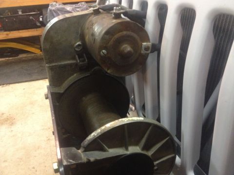2000 Jeep TJ - Close-up of a winch mechanism with a visible motor and drum, positioned before a vehicle's radiator grille.