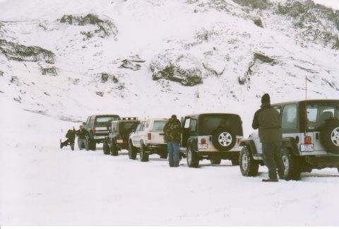 1996 Ford Bronco - Several SUVs are lined up in a snowy environment, with a few individuals visible near the vehicles.
