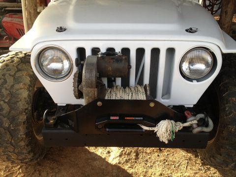 2000 Jeep TJ - Front view of a white Jeep Wrangler, equipped with a winch and large tires, showing its iconic grille.