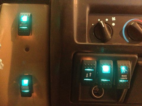 2000 Jeep Wrangler - Illuminated auxiliary switches for front air locker and rock lights are visible on the vehicle's interior dashboard.