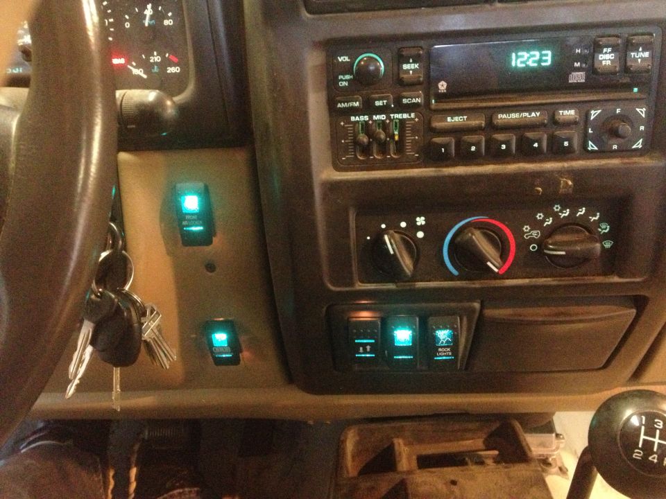 2000 Jeep TJ interior showing dashboard with radio, climate controls, and aftermarket auxiliary switches