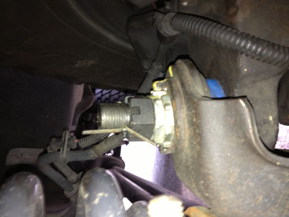 Close-up of a vehicle's suspension component, possibly a spindle or knuckle, with a large nut and cotter pin visible