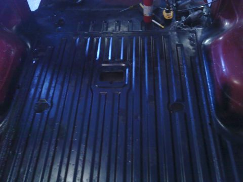 1978 Ford Bronco - The interior cargo area of a 1978 Ford Bronco shows a dark, ribbed floor with a fire extinguisher mounted on the side.
