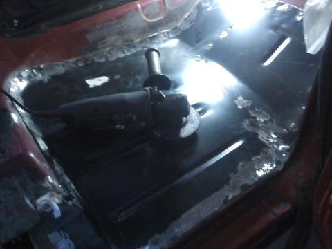 1978 Ford Bronco - Grinding tool on a vehicle's floor pan, showing rust and repair work.