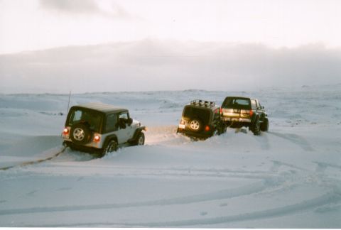 1996 Ford Bronco - Three SUVs struggle in deep snow, with one vehicle appearing to tow another.