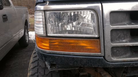 1995 Ford Bronco - Close-up of the front corner of a 1995 Ford Bronco, parked next to another vehicle.