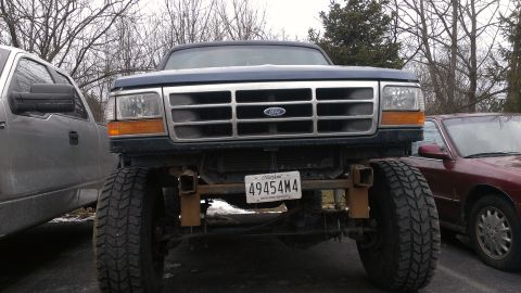 1995 Ford Bronco - This Ford truck features a prominent grille and large tires, parked between two other vehicles.