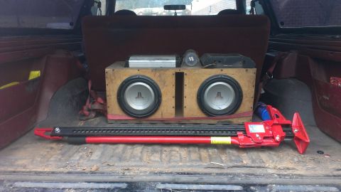 1995 Ford Bronco - The cargo area of a vehicle contains a custom subwoofer box and a hi-lift jack.