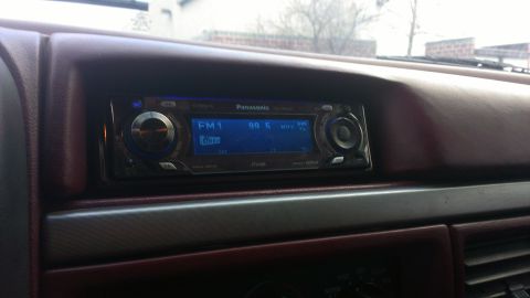 1995 Ford Bronco - The interior of a vehicle displays a maroon dashboard and a Panasonic car stereo system.