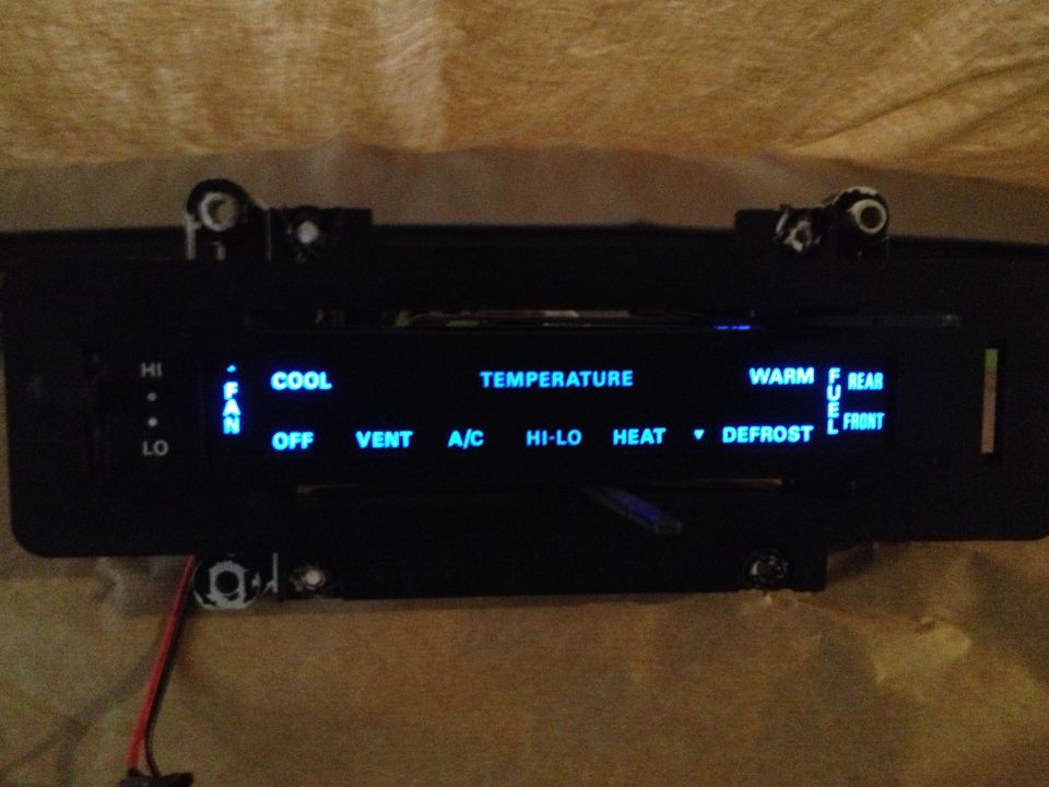 Vehicle climate control panel with illuminated blue text for fan speed, temperature, and mode selection