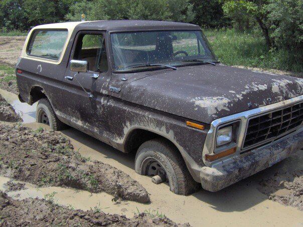 Muddy Ford Bronco stuck in a muddy ditch, front end partially submerged