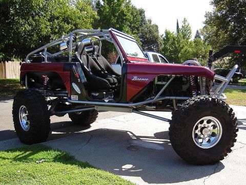 1967 Ford Mustang - A heavily modified off-road vehicle, identified as a Bronco, sits parked on a paved surface.