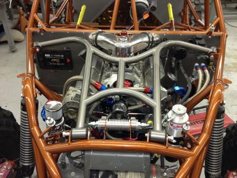 1967 Ford Mustang - The engine bay of a custom-built dune buggy features a V8 engine, chrome intake, and extensive roll cage tubing.
