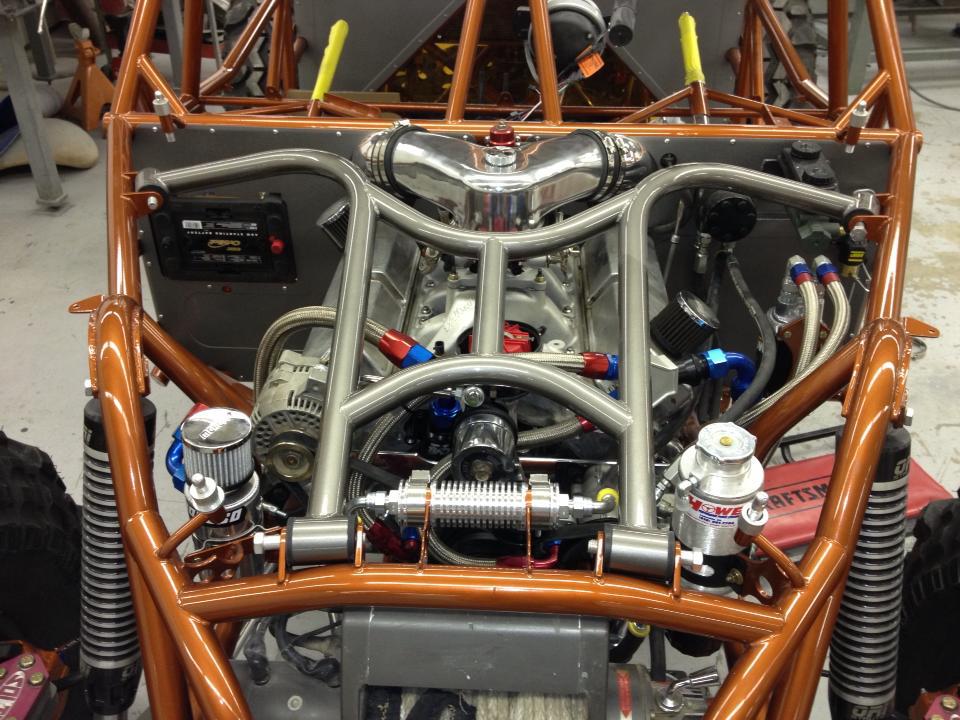 Engine bay of a custom dune buggy with a V8 engine, chrome intake, and orange roll cage