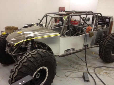 1967 Ford Mustang - An unfinished off-road buggy with a custom roll cage and large tires sits in a workshop.
