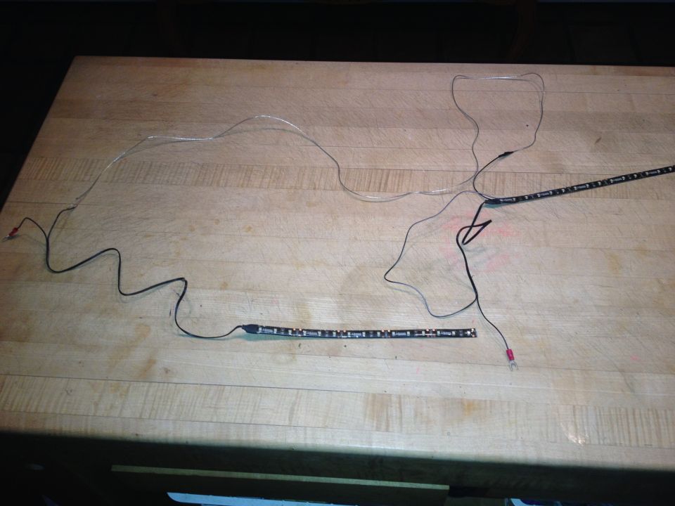 Two LED light strips with wiring laid out on a wooden surface