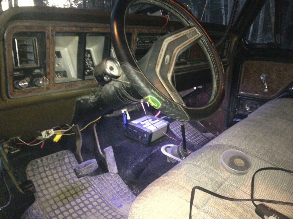 Interior of an old truck or SUV, showing dashboard, steering wheel, pedals, and aftermarket stereo wiring