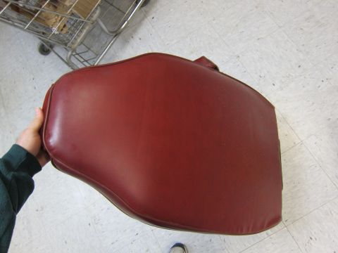 1991 Ford LTD Crown Victoria - A red vinyl car seat cushion is held up for inspection, with a shopping cart visible in the background.