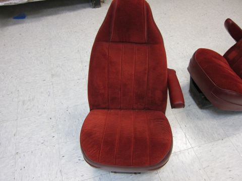 1991 Ford LTD Crown Victoria - Pair of red velour bucket seats, likely from a sedan or coupe, shown in a workshop setting.