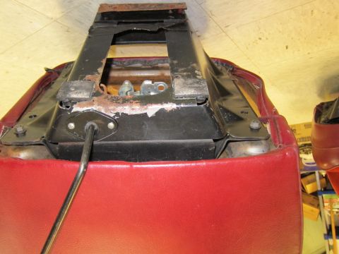 1991 Ford LTD Crown Victoria - Close-up of a car seat's internal frame and red upholstery, showing signs of wear and rust.
