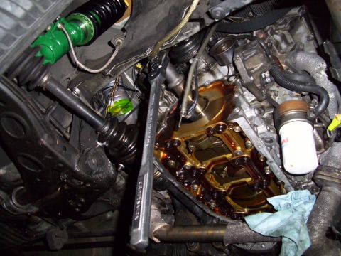 1995 Ford Probe - Close-up view of a car's engine bay with the oil pan removed, revealing internal mechanics and a wrench in place.