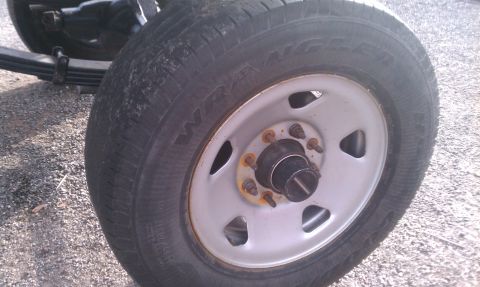 1995 Ford Bronco - A close-up view of a vehicle's wheel and suspension system, showing the tire and hub assembly.