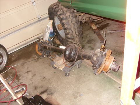 1967 Ford F-250 - A green truck's rear axle assembly is shown on a dolly in a garage setting.