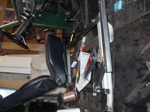1967 Ford F-250 - The interior of a vehicle shows a black seat, steering wheel, and various tools and wiring, suggesting ongoing work.