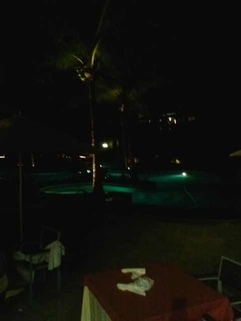 1960 Ford Falcon - Nighttime view of a resort pool area with illuminated water and tropical foliage.