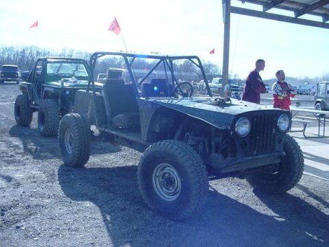 1992 Ford Bronco - Custom off-road buggy and another vehicle at an outdoor event. Two people are standing in the background.