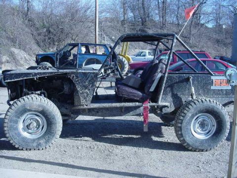 1992 Ford Bronco - A custom-built buggy with a roll cage and large tires sits in a lot, with other vehicles in the background.