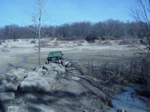 1992 Ford Bronco - An off-road vehicle traverses a challenging rocky path under a clear blue sky.