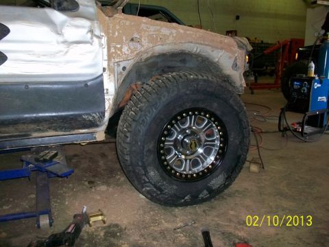 1999 Isuzu Vehicross - Vehicle body damage and custom wheel are visible, with welding equipment nearby.