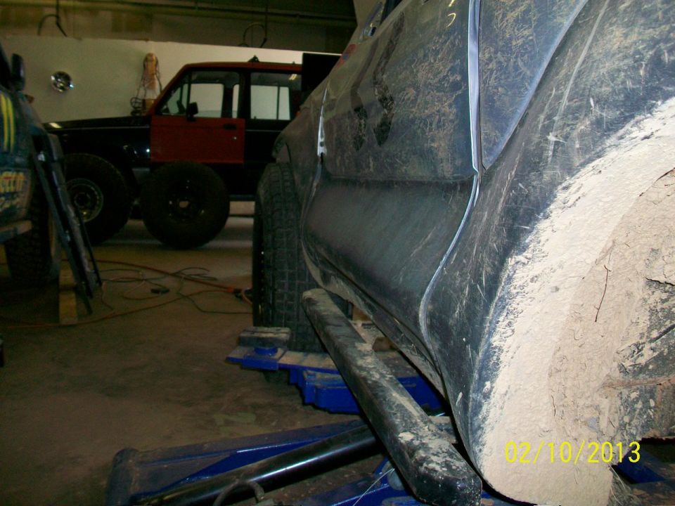 Muddy SUV on lift, another red SUV in background