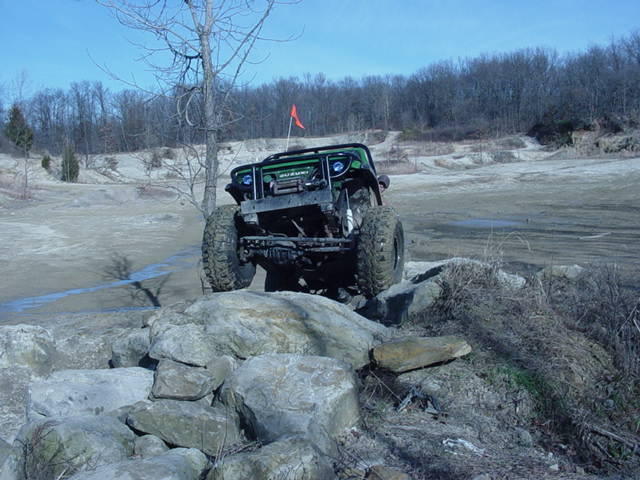 Green off-road SUV climbing rocks