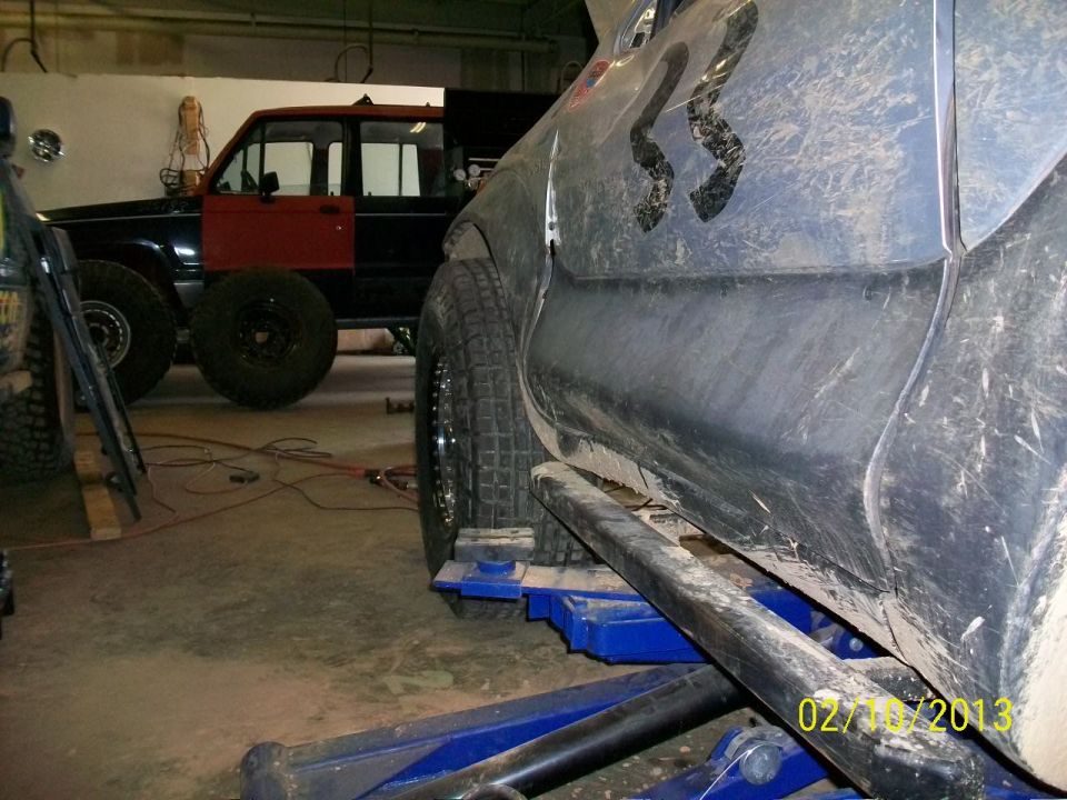 SUV on a lift, side view, with large off-road tires and custom graphics on the door