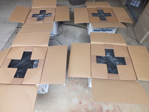 2003 Ford Crown Victoria - Several open boxes marked with black tape X on concrete, one labeled Wheel Replicas in background.