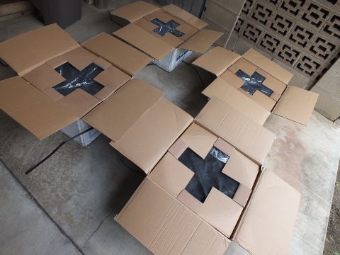 2003 Ford Crown Victoria - Group of open shipping boxes each bearing a black tape X mark, scattered across a concrete floor.