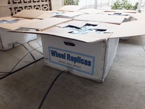 2003 Ford Crown Victoria - white Wheel Replicas Quality Alloy Wheels carton, opened, among other boxes on a patio floor.