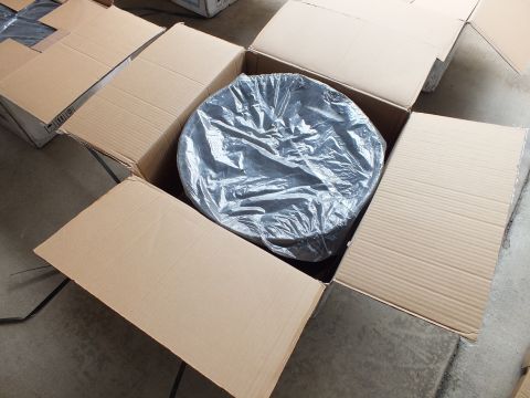 2003 Ford Crown Victoria - Round wheel sealed in plastic wrap nested in an open carton, surrounded by other open boxes on concrete.
