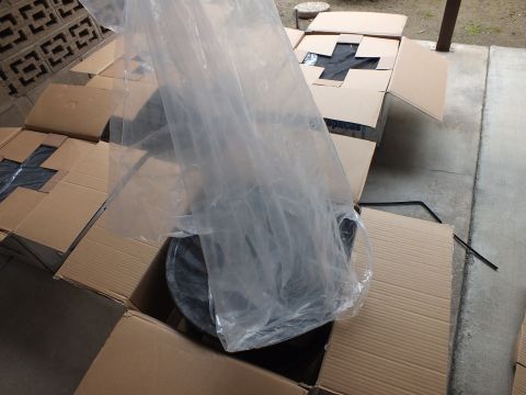 2003 Ford Crown Victoria - Clear plastic film lifted off a wrapped wheel inside an open box, with taped X boxes in the background.