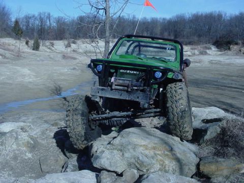 1992 Ford Bronco - Off-road Suzuki Samurai navigating a rocky terrain with large tires.